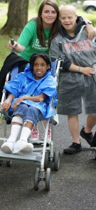 Photo of three smiling young women: one in a wheelchair, another with developmental disability, and an Easterseals employee